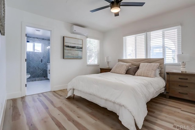 bedroom with ceiling fan, light wood-type flooring, a wall mounted air conditioner, and ensuite bathroom