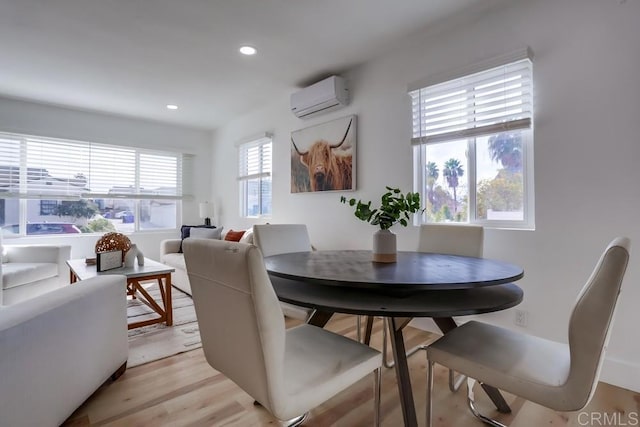 dining area with an AC wall unit and light hardwood / wood-style flooring