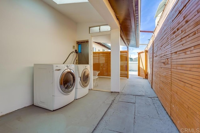 laundry room featuring wood walls and washing machine and dryer