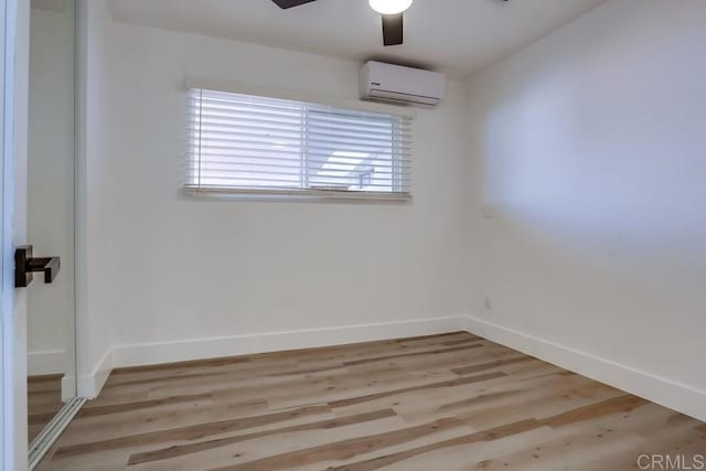 unfurnished room with light wood-type flooring, a wall mounted air conditioner, and ceiling fan