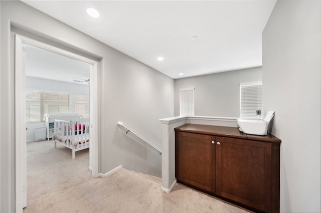 hall with light colored carpet and sink