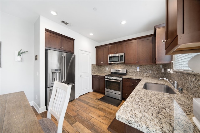 kitchen featuring light stone counters, sink, dark brown cabinetry, and stainless steel appliances