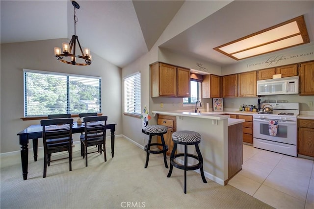 6279 Twinberry Cir Unit 7, Avila Beach, CA 93424 - kitchen featuring white appliances, a chandelier, brown cabinets, a peninsula, and lofted ceiling