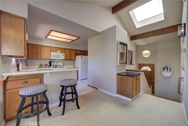 6279 Twinberry Cir Unit 7, Avila Beach, CA 93424 - kitchen featuring white appliances, a skylight, a peninsula, brown cabinets, and a kitchen bar