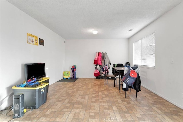 rec room featuring visible vents, a textured ceiling, and baseboards