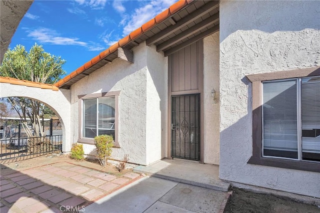 view of exterior entry featuring fence and stucco siding