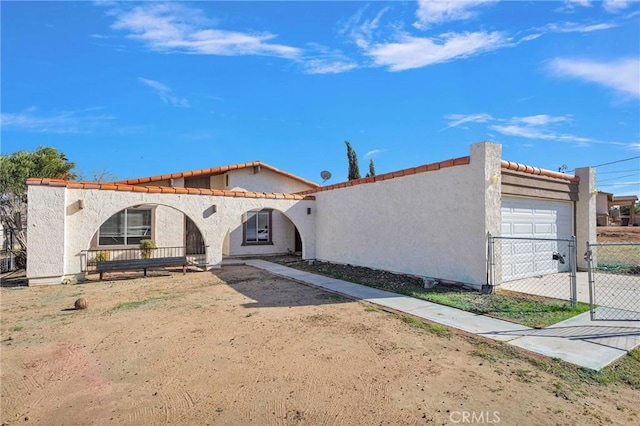 mediterranean / spanish house with driveway, an attached garage, a gate, fence, and stucco siding