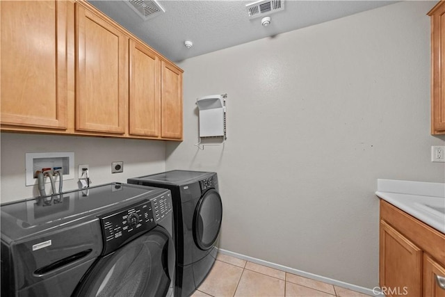 washroom featuring washing machine and clothes dryer, sink, cabinets, a textured ceiling, and light tile patterned floors