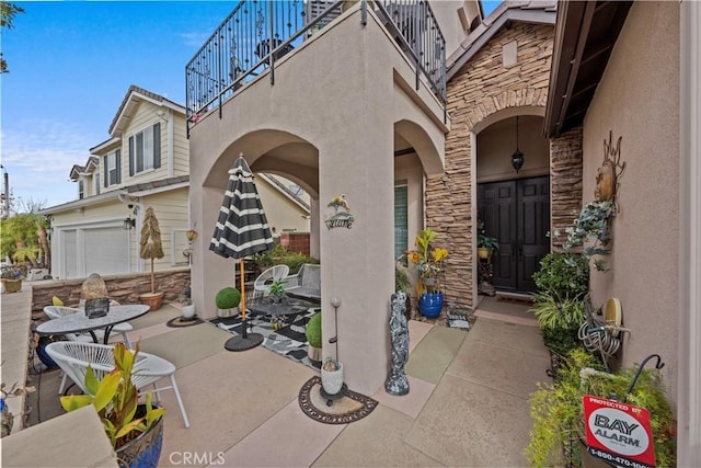 property entrance featuring a balcony, a garage, and a patio