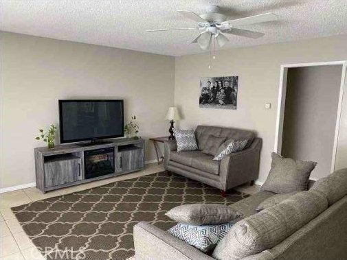 tiled living room with a textured ceiling and ceiling fan