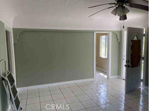 tiled spare room with ceiling fan