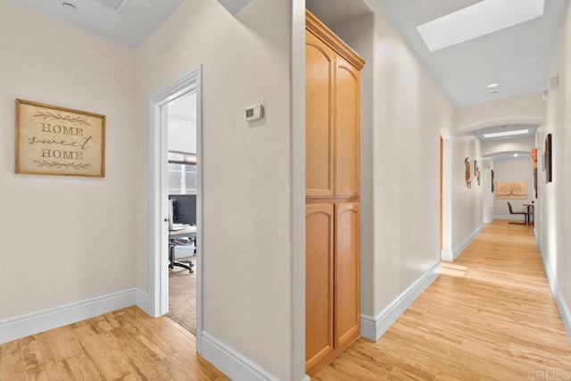 corridor featuring light hardwood / wood-style floors and a skylight