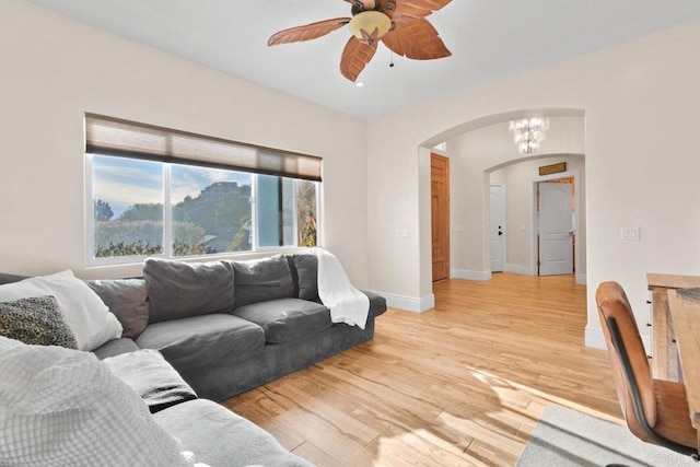 living room with ceiling fan with notable chandelier, a healthy amount of sunlight, and light hardwood / wood-style floors