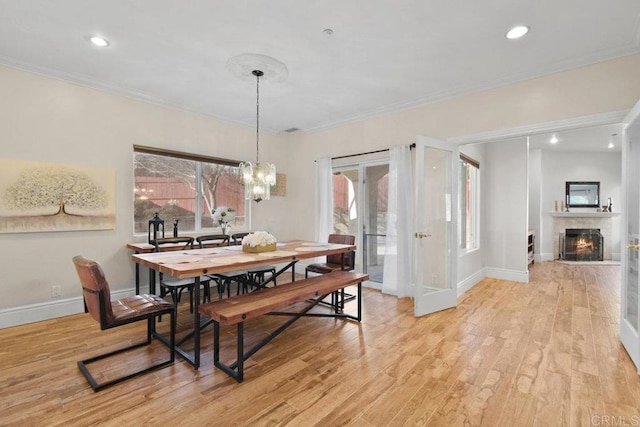 dining area with crown molding, a notable chandelier, and light wood-type flooring