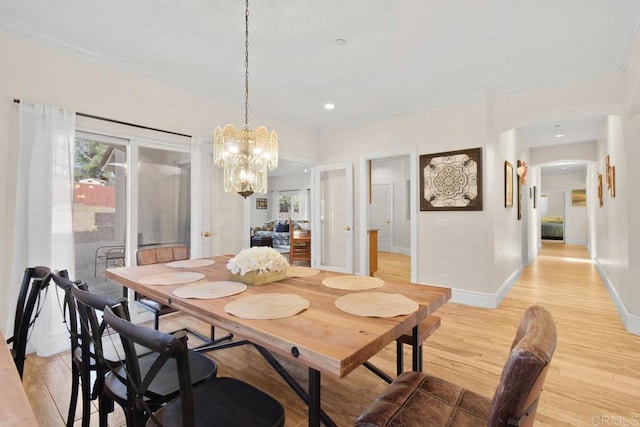 dining area with ornamental molding, a notable chandelier, and light wood-type flooring