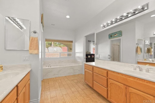 bathroom featuring a relaxing tiled tub, hardwood / wood-style floors, and vanity