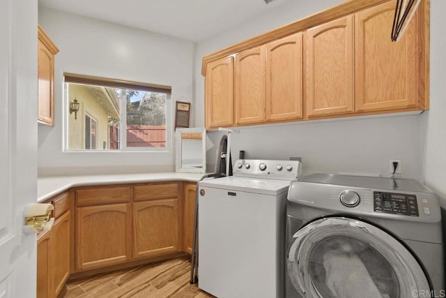 washroom featuring light hardwood / wood-style floors, cabinets, and washer and clothes dryer