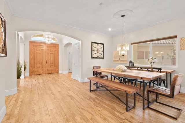 dining space featuring ornamental molding, an inviting chandelier, and light hardwood / wood-style floors