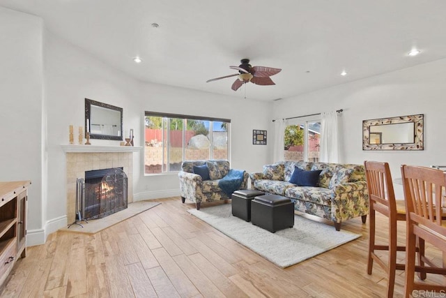 living room featuring a fireplace, light hardwood / wood-style flooring, and ceiling fan