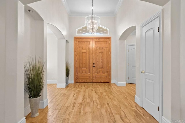 entrance foyer featuring light hardwood / wood-style flooring, ornamental molding, and an inviting chandelier