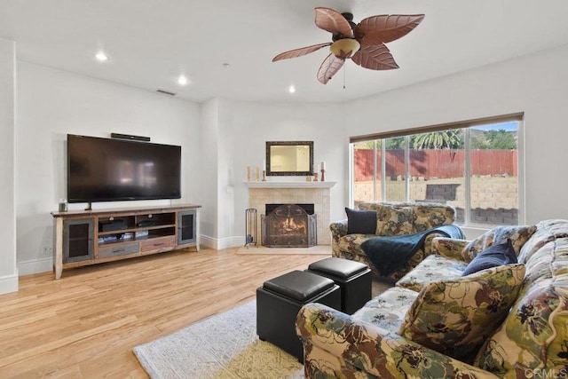 living room with ceiling fan, hardwood / wood-style floors, and a tiled fireplace