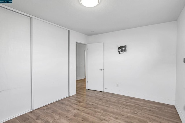 unfurnished bedroom with light hardwood / wood-style floors and a closet