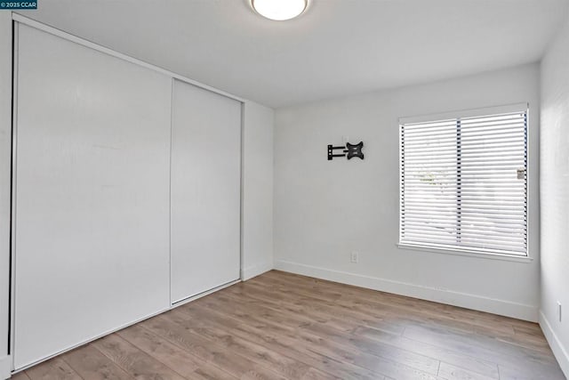 unfurnished bedroom featuring light wood-type flooring and a closet