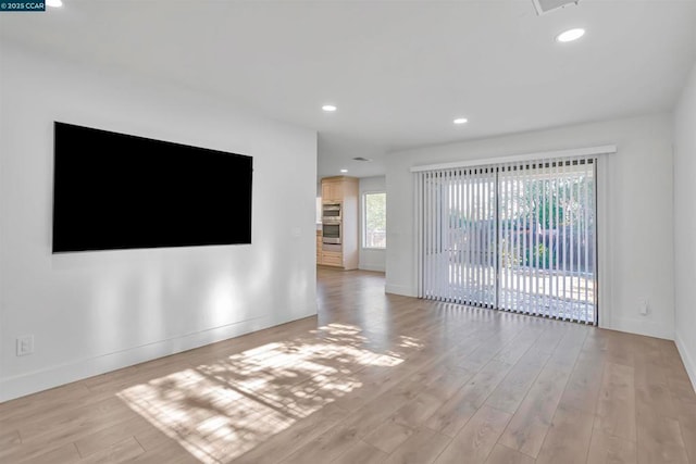 unfurnished living room featuring plenty of natural light and light hardwood / wood-style flooring