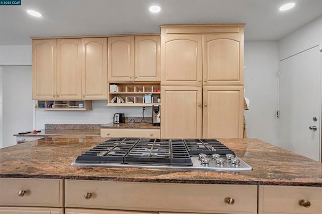 kitchen featuring light brown cabinets, stainless steel gas cooktop, and dark stone counters