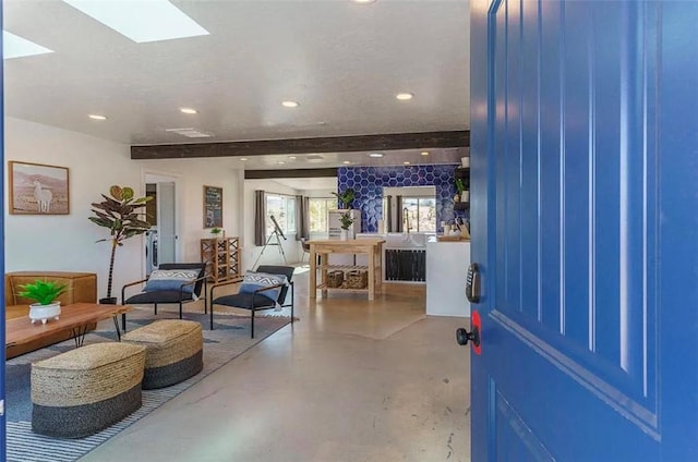 foyer featuring concrete flooring, beamed ceiling, and a skylight