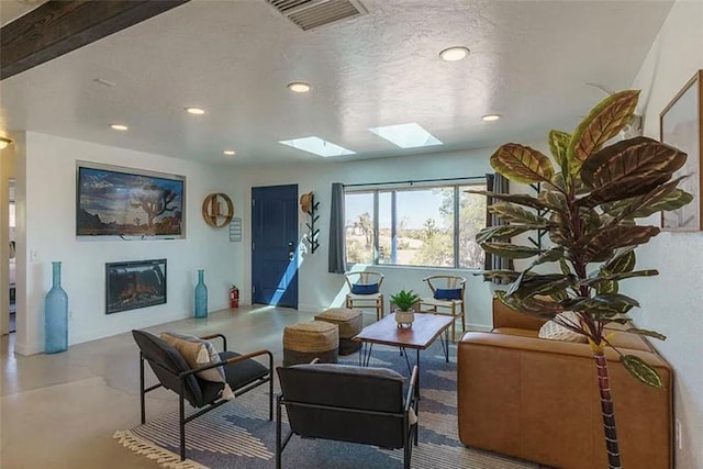 living room with a skylight, beam ceiling, and a textured ceiling