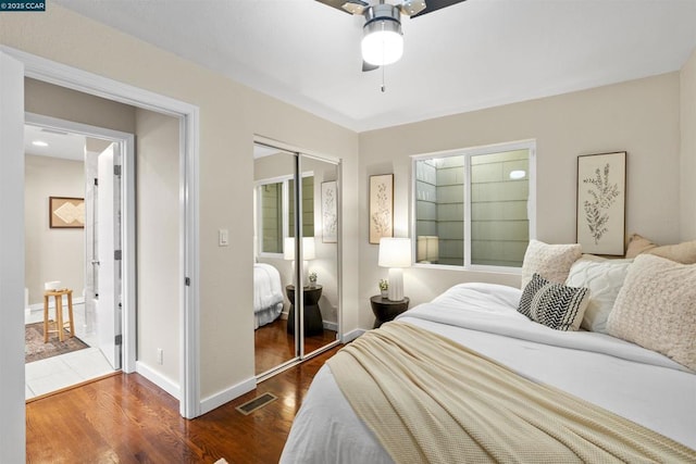 bedroom with ceiling fan, dark wood-type flooring, and a closet