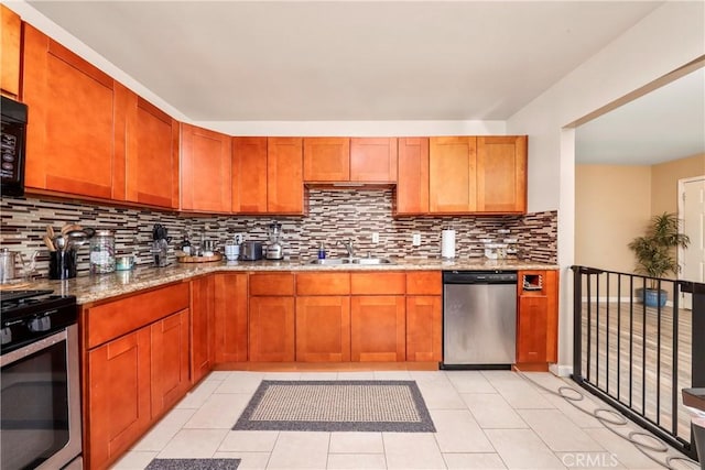 kitchen featuring sink, tasteful backsplash, light stone countertops, light tile patterned flooring, and stainless steel appliances