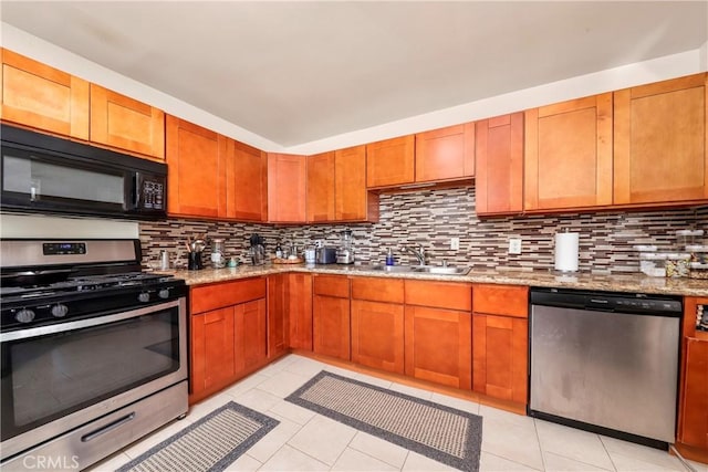 kitchen with stainless steel appliances, tasteful backsplash, sink, light stone counters, and light tile patterned floors