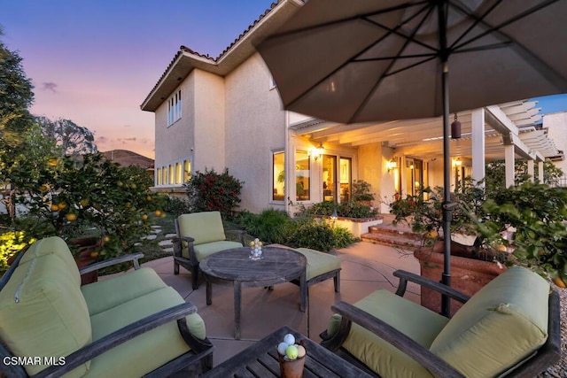 patio terrace at dusk featuring outdoor lounge area and a pergola