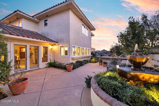 back house at dusk with a patio area