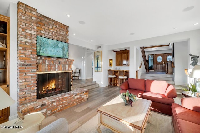 living room featuring a brick fireplace and light hardwood / wood-style flooring