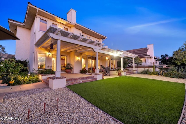 back house at dusk featuring a yard, a pergola, and a patio area