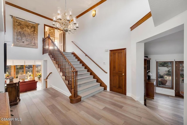 stairs featuring a high ceiling, ornamental molding, hardwood / wood-style flooring, and an inviting chandelier