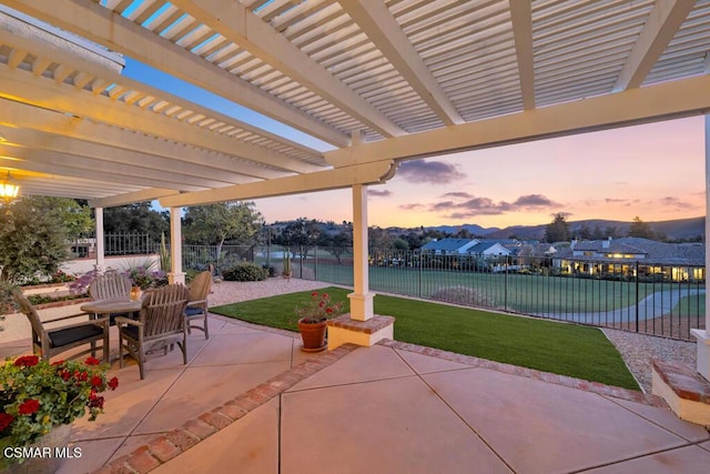 patio terrace at dusk featuring a yard and a pergola