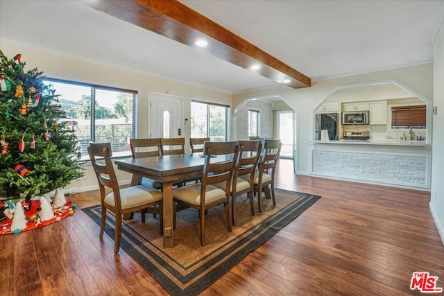 dining room featuring dark wood-type flooring, beamed ceiling, and ornamental molding