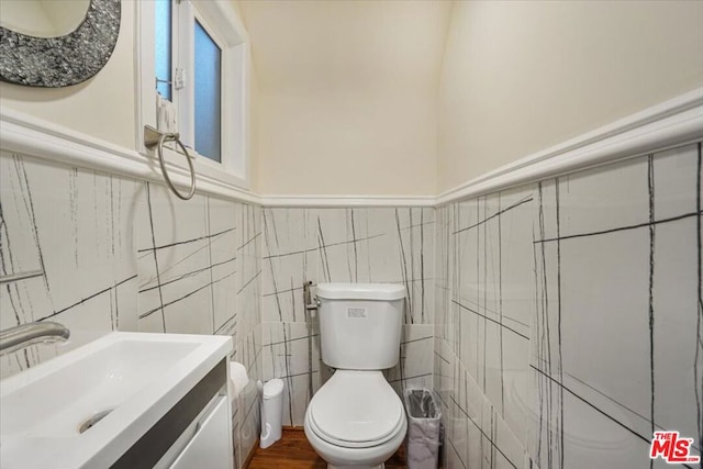 bathroom with tile walls, toilet, and vanity