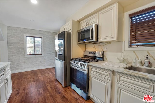 kitchen with light stone countertops, stainless steel appliances, and dark wood-type flooring