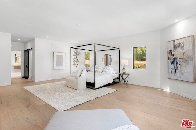 bedroom featuring light wood-type flooring, multiple windows, and a barn door