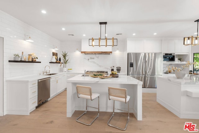 kitchen featuring an island with sink, white cabinets, pendant lighting, and stainless steel appliances