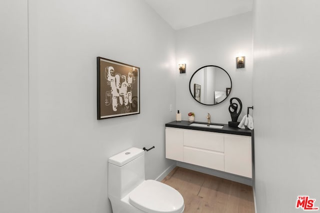 bathroom with hardwood / wood-style floors, toilet, and vanity