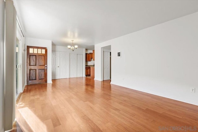 unfurnished living room featuring a chandelier and light hardwood / wood-style flooring