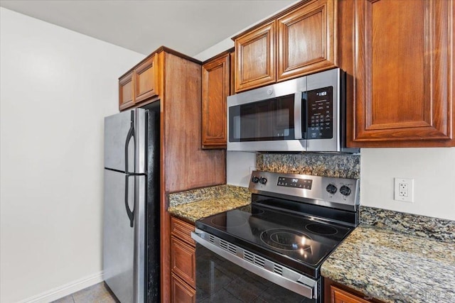 kitchen featuring dark stone counters, light tile patterned floors, and appliances with stainless steel finishes