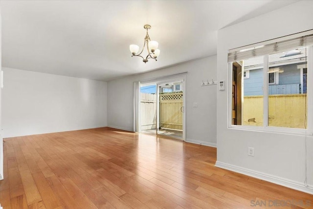 unfurnished room featuring light hardwood / wood-style flooring and an inviting chandelier