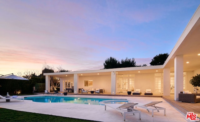 pool at dusk featuring a patio area and an outdoor living space